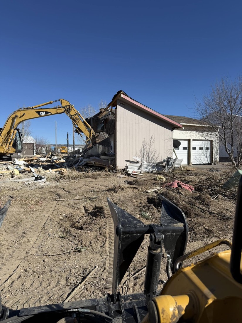 Excavator working beside a partially removed building