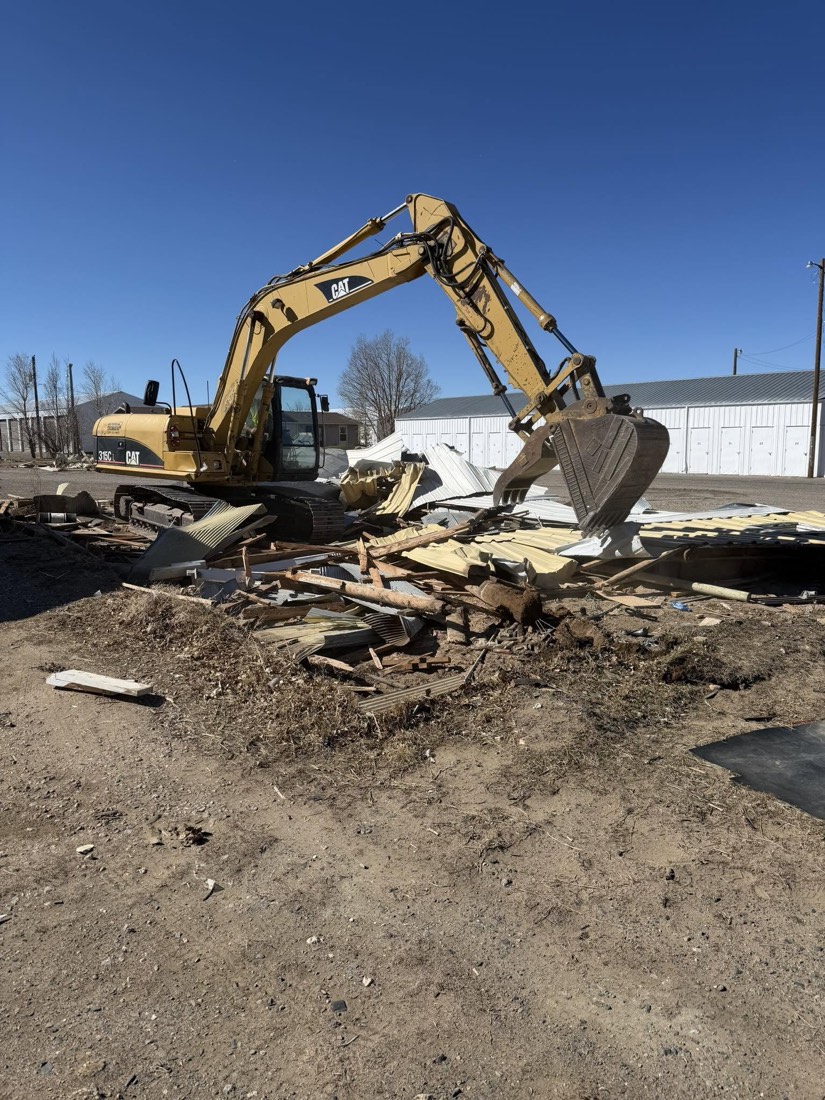 Excavator clearing wood and building materials