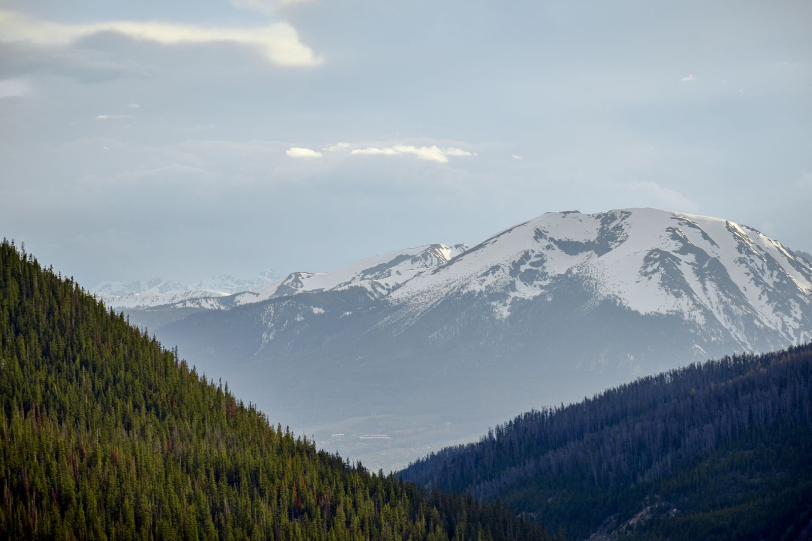Snow-covered Rocky Mountains above a forested Colorado valley
